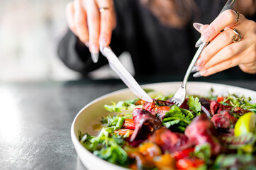 woman hands with knife and fork eat Fresh salad