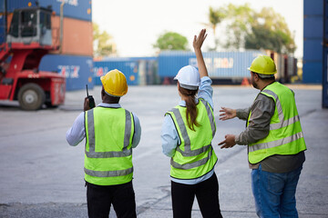 back view workers or engineer using walkie talkie and showing gesture to crane car in containers...