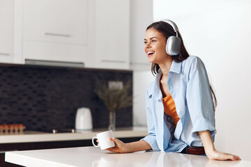 Woman enjoying a peaceful morning at home, listening to music with headphones and drinking coffee...