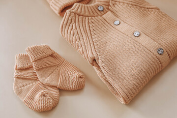 Knitted jumpsuit for a newborn on a beige background. Outerwear for toddlers for walks in autumn or spring