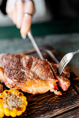 woman hands with fork and knife eating beef steak in cafe