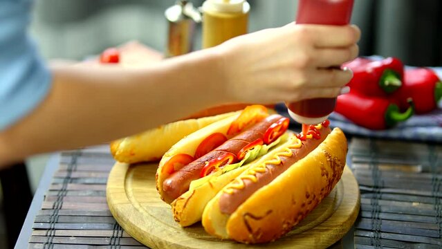 Tasty hot dog with grilled sausage . Adding mustard to hot dog	