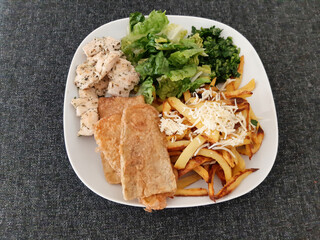 Homemade grilled chicken with grilled zucchini, green salad, french fries, cheese and parsley