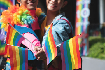 Two gay men join in the fun at the Pride parade, showing and waving flags in celebration of Pride...