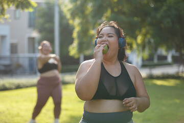 Asian female overweight in sportswear and headphone eating apple  aerobic exercise physical...