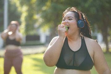 Asian female overweight in sportswear and headphone eating apple  aerobic exercise physical...