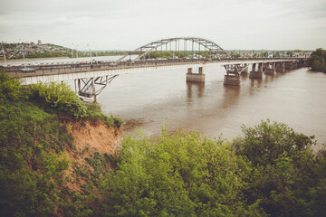 Arch bridge over water with city skyline in the background