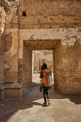 Fototapeta na wymiar Female traveler with a backpack walking through an open stone archway