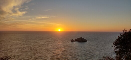 the sun sets over the ocean, as seen from a cliff