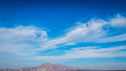 A mountain range against the sky filled with white fluffy clouds