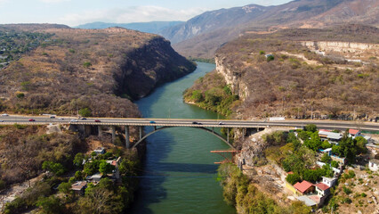 a view from above the bridge with cars on it, showing a green river and
