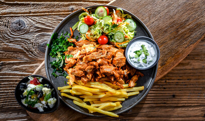 Kebab served with french fries, vegetable salad and tzatziki