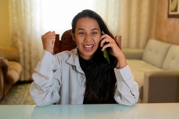 Female adult speaking on a phone with an excited expression on her face