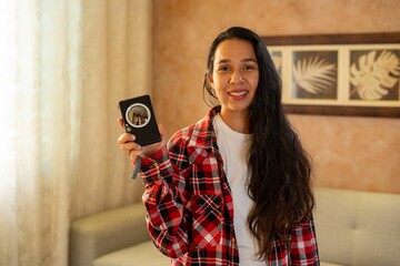 a woman holding up her black cell phone next to her couch