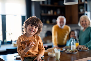 Portrait of a cute little boy with his favorite croissant.  Food and happy kids. Carefree childhood. Breakfast and family.