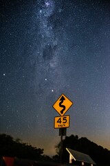 Yellow traffic sign against the background of the starry night sky.