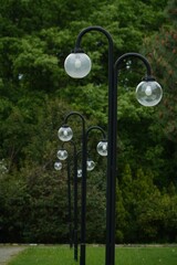 Scenic outdoor scene with lamp posts, each topped with a glass ball, in a lush green park setting