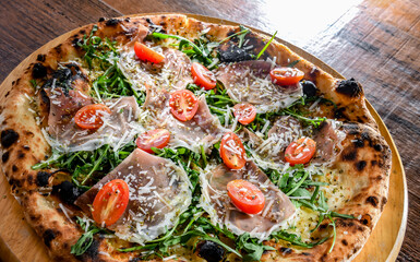 Pizza Italiana served with ham, cheese, tomatoes and rucola