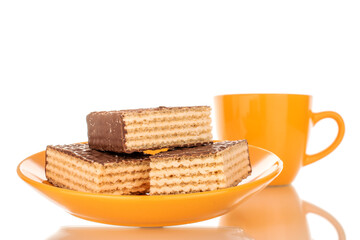 Obraz na płótnie Canvas Three sweet chocolate wafers on a ceramic saucer with a cup in the background, macro, isolated on a white background.