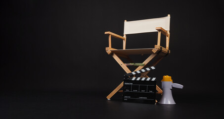 Director chair with a clapper board and megaphone on black background.