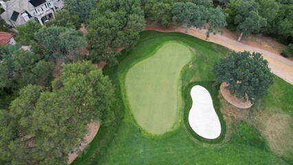 Aerial view of a golf course located in a city with lush trees surrounding the playing area