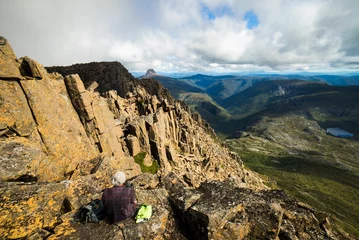 Papier peint Mont Cradle Hiker sitting on a rocky mountaintop overlooking the scenic landscape. Cradle Mountain, Australia.