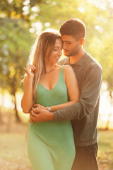 Fototapeta premium Vertical shot of an in love young couple hugging in the light of sunset.