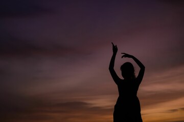 a woman doing a handstand pose at sunset on a beach