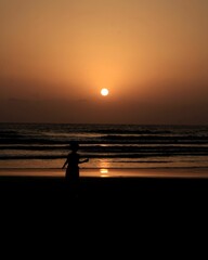 Silhouette of a person enjoying a peaceful evening stroll along the beach at sunset.