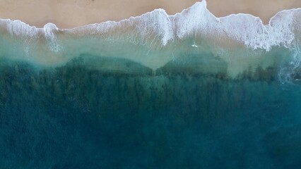 Fototapeta na wymiar Aerial view of sea waves crashing against a beach in the daylight