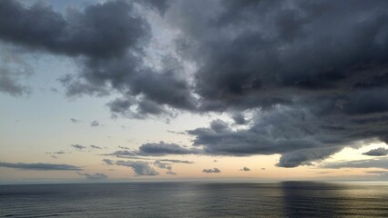 Drone view of sea waves surrounded by cliffs under a cloudy sky in the evening