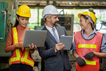 group of diversity business man manager Engineer and asian woman factory worker in hard hat working with tablet and laptop computer in industry manufacturing Factory . Industrial