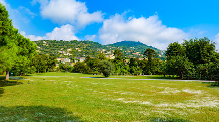 Genoa, Italy. In the Municipal Park of Nervi Gropallo, vast green meadows near Villa Grimaldi. Some people are relaxing in the park. In the background the hills of Genoa Sant'Ilario.