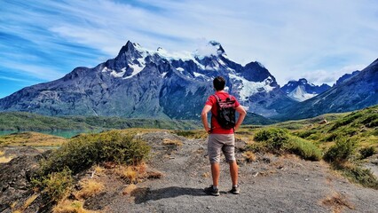 Backpacker stands against the backdrop of majestic mountains. Torres del Paine National Park. - obrazy, fototapety, plakaty