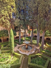 Spectacular fountain surrounded by lush greenery in the sun-soaked Alhambra gardens in Spain