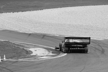 Black and white shot of a racing car speeding around a track