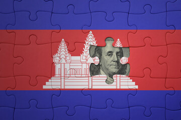puzzle with the national flag of cambodia and usa dollar banknote. finance concept