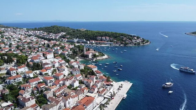 Drone shot over Harbor of Hvar with boats and ships and red roof houses on a sunny day