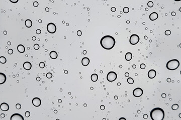 Rain drops on window glasses surface with cloudy background . Natural Pattern of raindrops isolated on cloudy background.