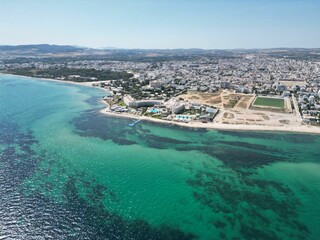 Fototapeta premium blue water with white buildings in the background and a sandy beach in front of it