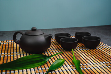 Black teapot and cups with bamboo leaves on a tray. Traditional tea ceremony.