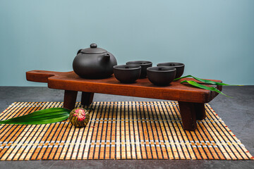Black teapot and cups with bamboo leaves on a tray. Traditional tea ceremony. Green Tea Composition with bamboo leaves, banner. Chinese traditional tea set, tea ceremony concept, top view, copy space.