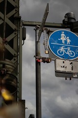 Image of a street sign with pedestrian and cyclist symbols located  below the traffic signals