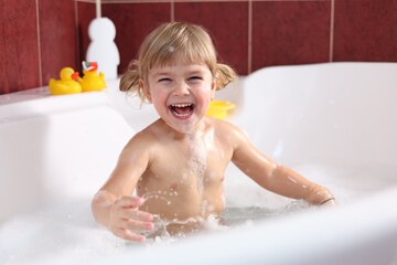 Happy girl bathing in tub at home