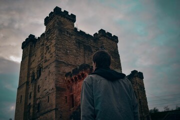 man looking up at tall tower against cloudy sky background at dusk