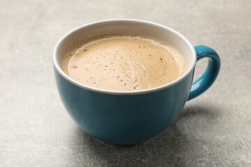 Cup of aromatic coffee on light grey table, closeup