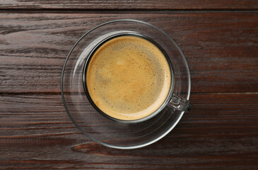 Cup of aromatic coffee on wooden table, top view