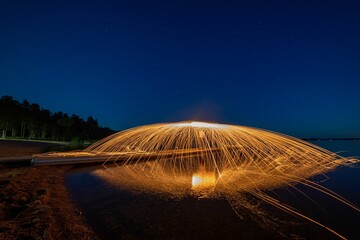 Night scene featuring a burning fire created by spinning steel wool with a long exposure.
