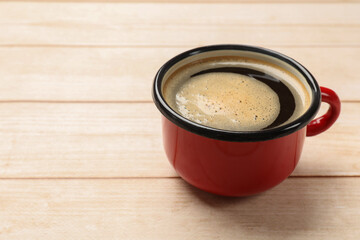 Cup of aromatic coffee on light wooden table, closeup. Space for text