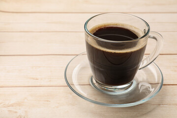 Cup of aromatic coffee on light wooden table, closeup. Space for text
